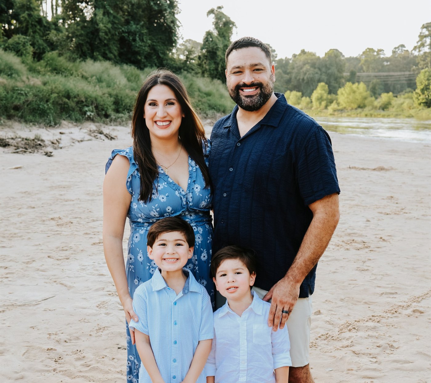 Jessica and her husband Derrick standing on a riverbank with their two young sons.